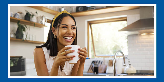 Image shows a smiling woman holding a white mug happy about her debt consolidation loan from houston highway credit union